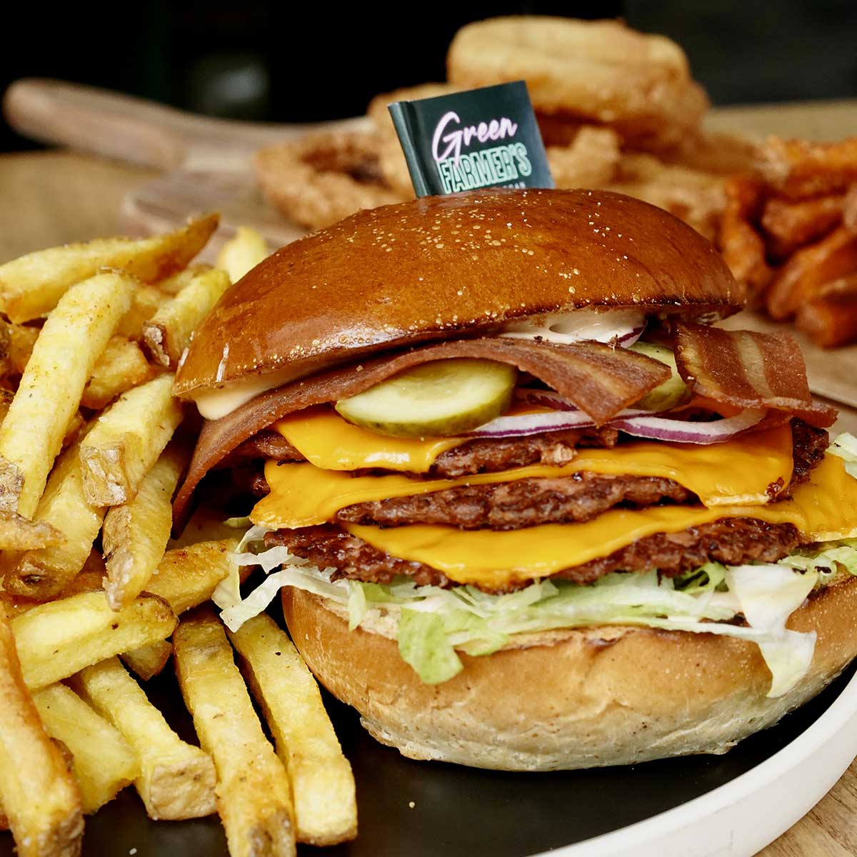 Gros plan sur un burger vegan Green Farmer's avec pick de marque et frites en arrière-plan